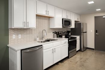 a kitchen with white cabinets and black appliances